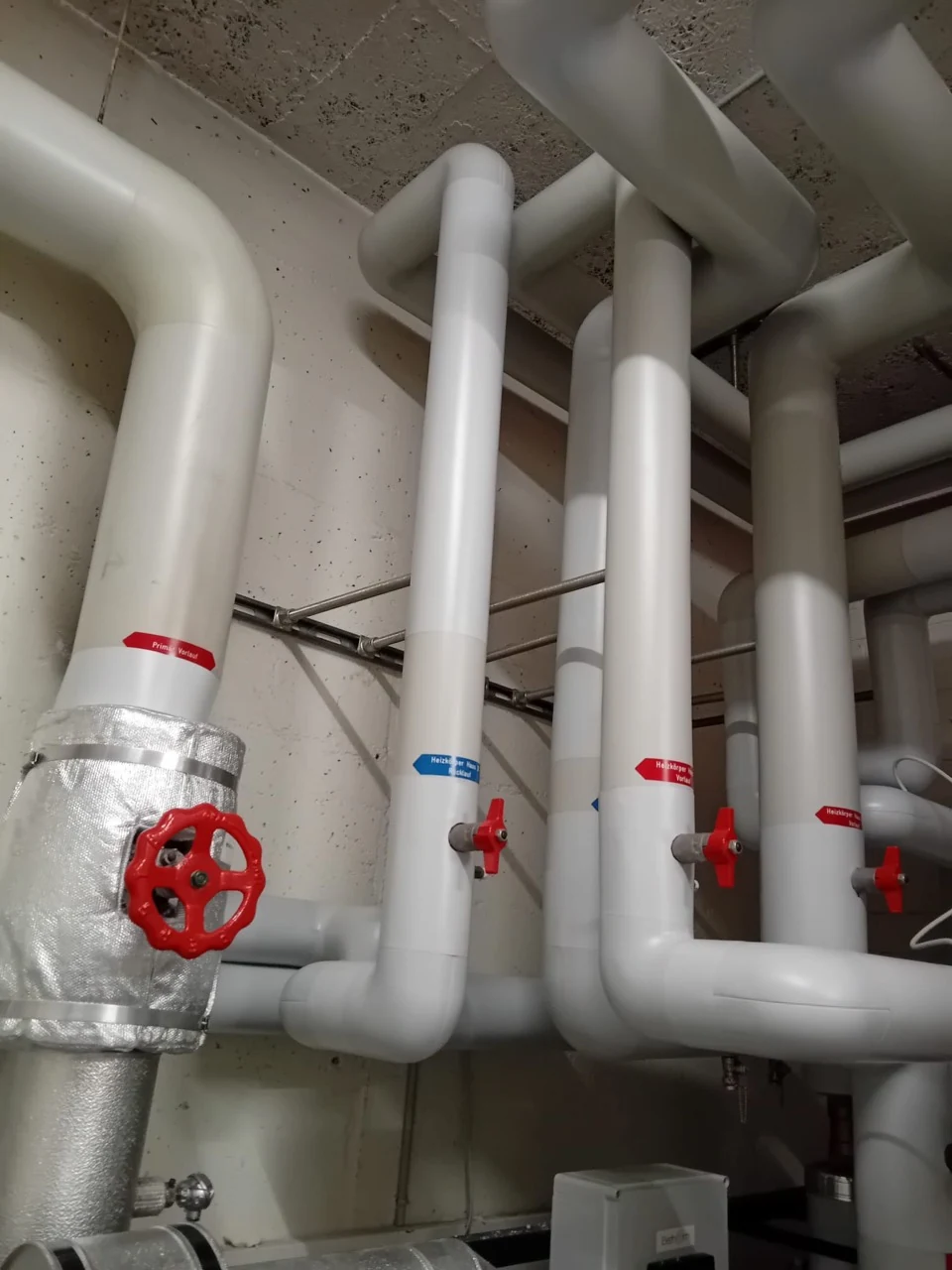 Mit PVC ummantelte Rohrleitungen und Bögen in einer Heizzentrale